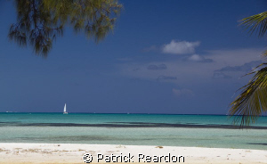 A sailboat passes by Cayman Kai, on the North shore of Gr... by Patrick Reardon 